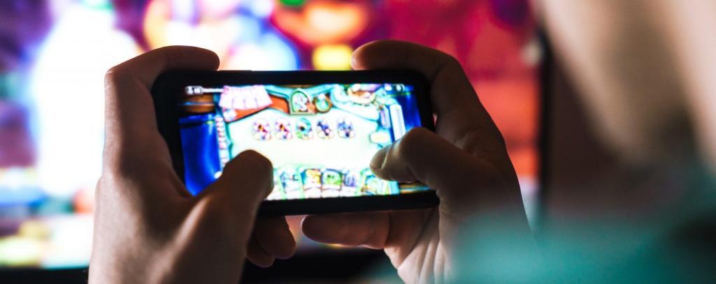 Image closeup of focused man playing video game on mobile phone