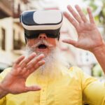 Senior hipster man using virtual reality headset outdoor – Metaverse concept – Focus on vr goggles